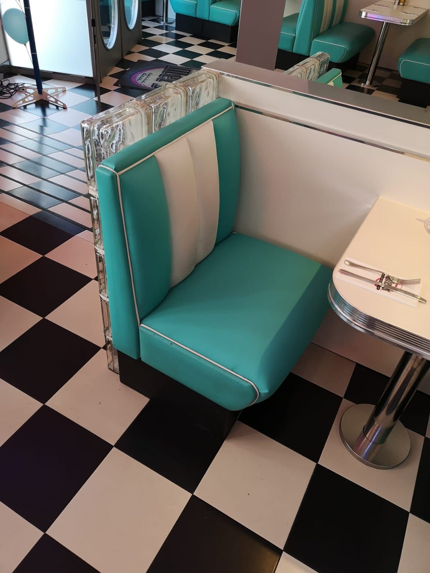 Banco de restaurante tapizado en turquesa y blanco junto a una mesa