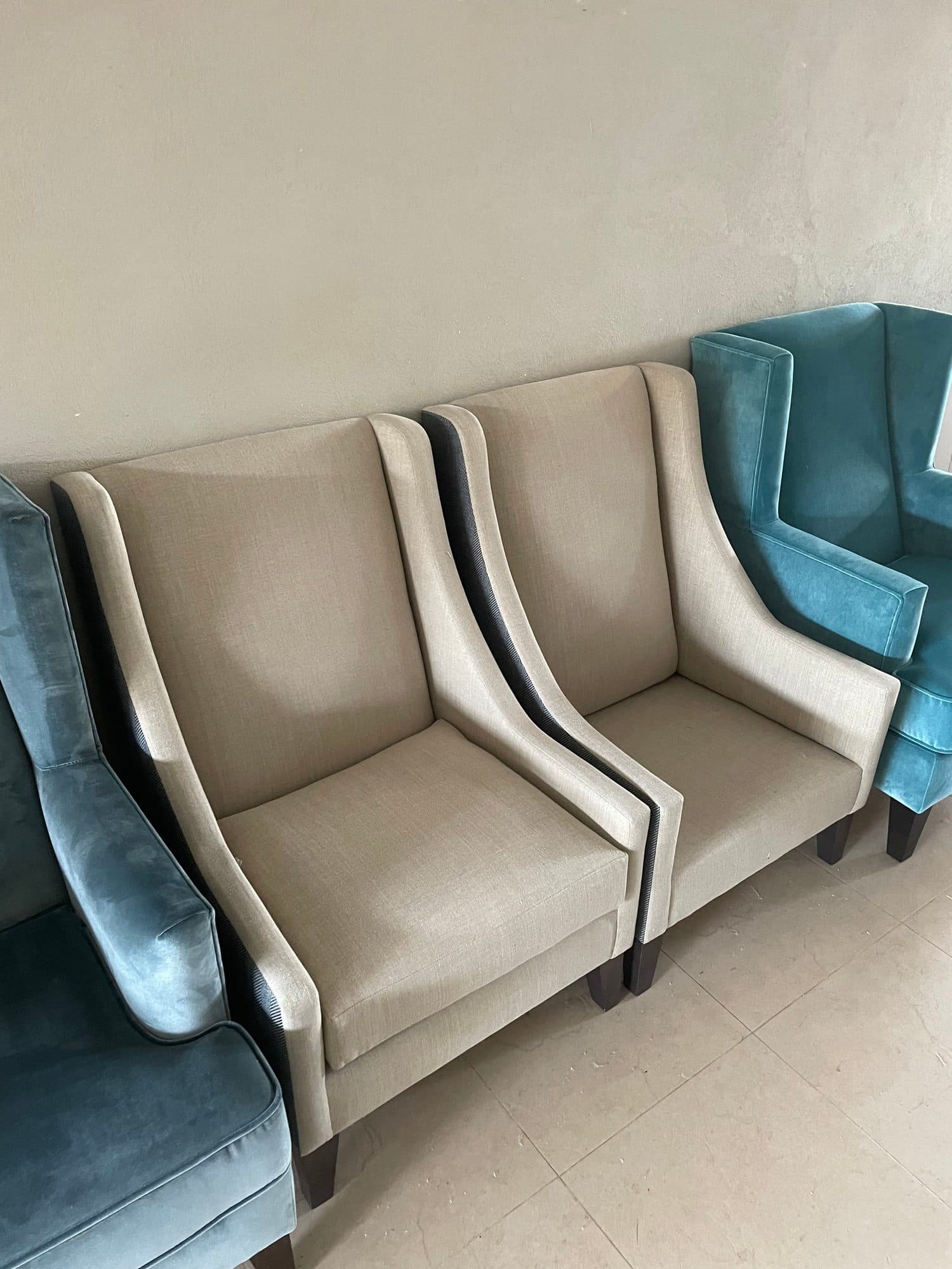 Butacas fabricadas a medida en tejido beige con vivos en contraste junto a otras en terciopelo verde azulado