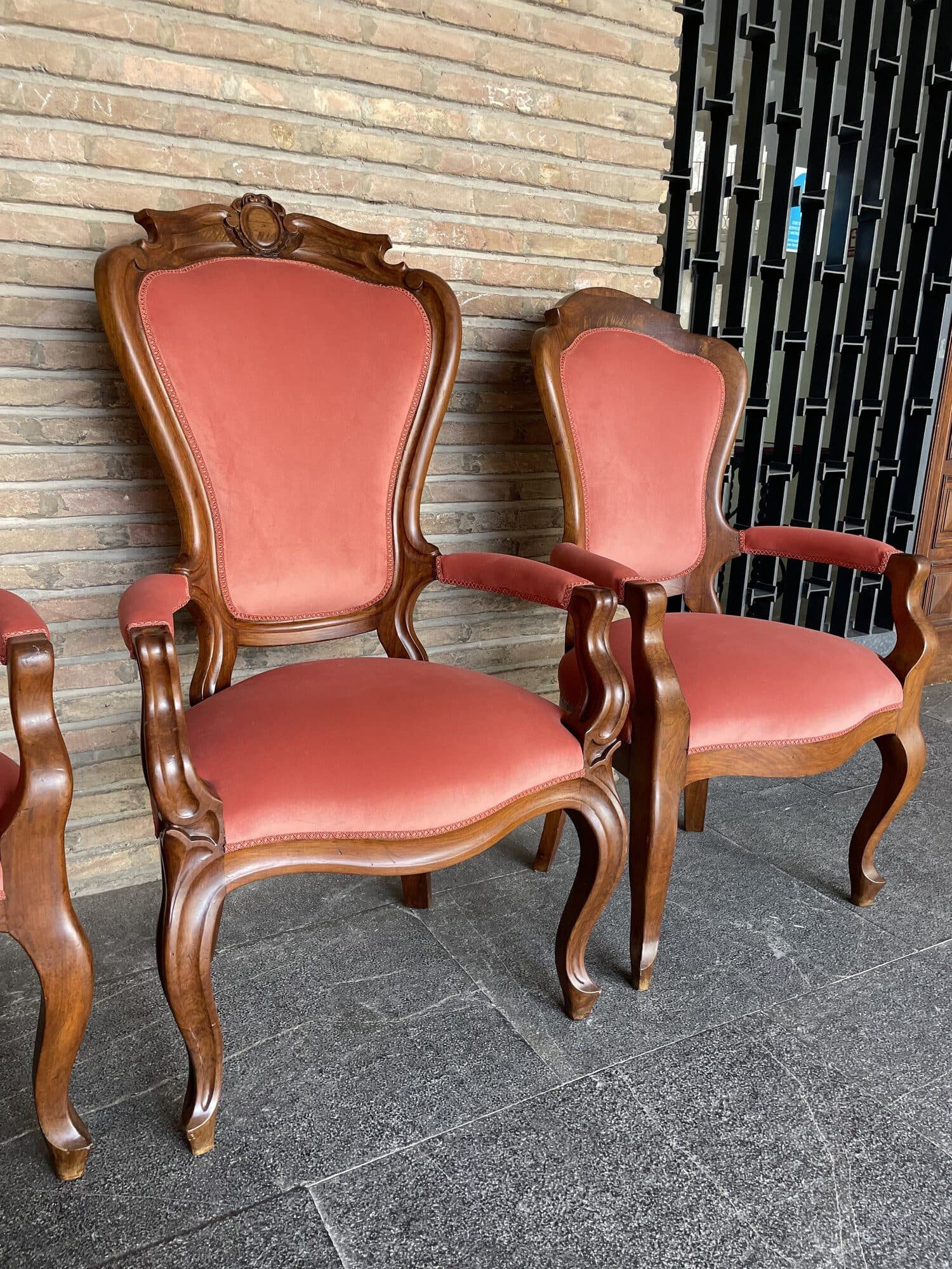 Pareja de butacas clásicas de madera tallada con respaldo de copete, retapizadas en terciopelo coral