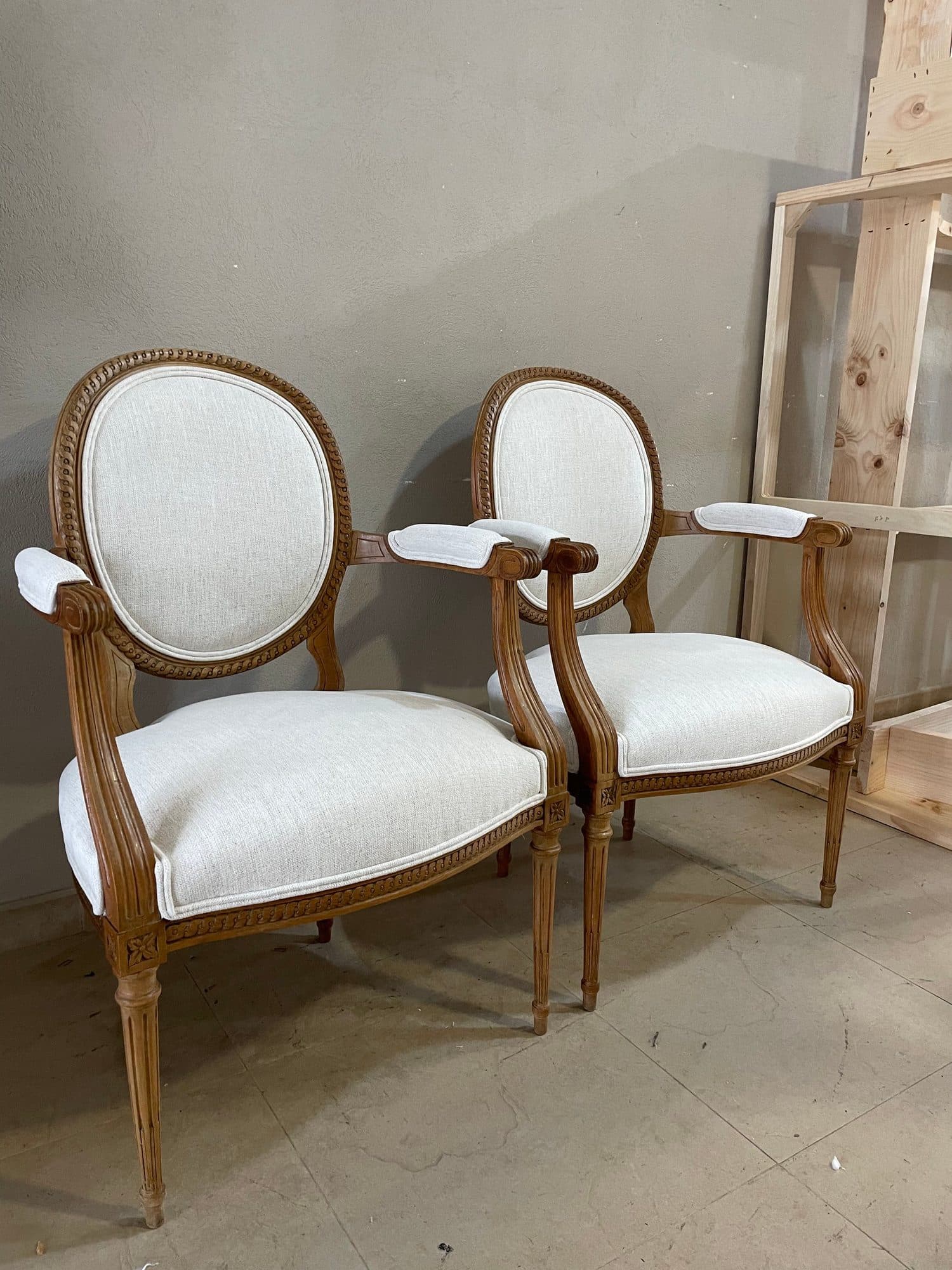 Dos butacas medallón de estilo Luis XVI tapizadas en blanco en el taller