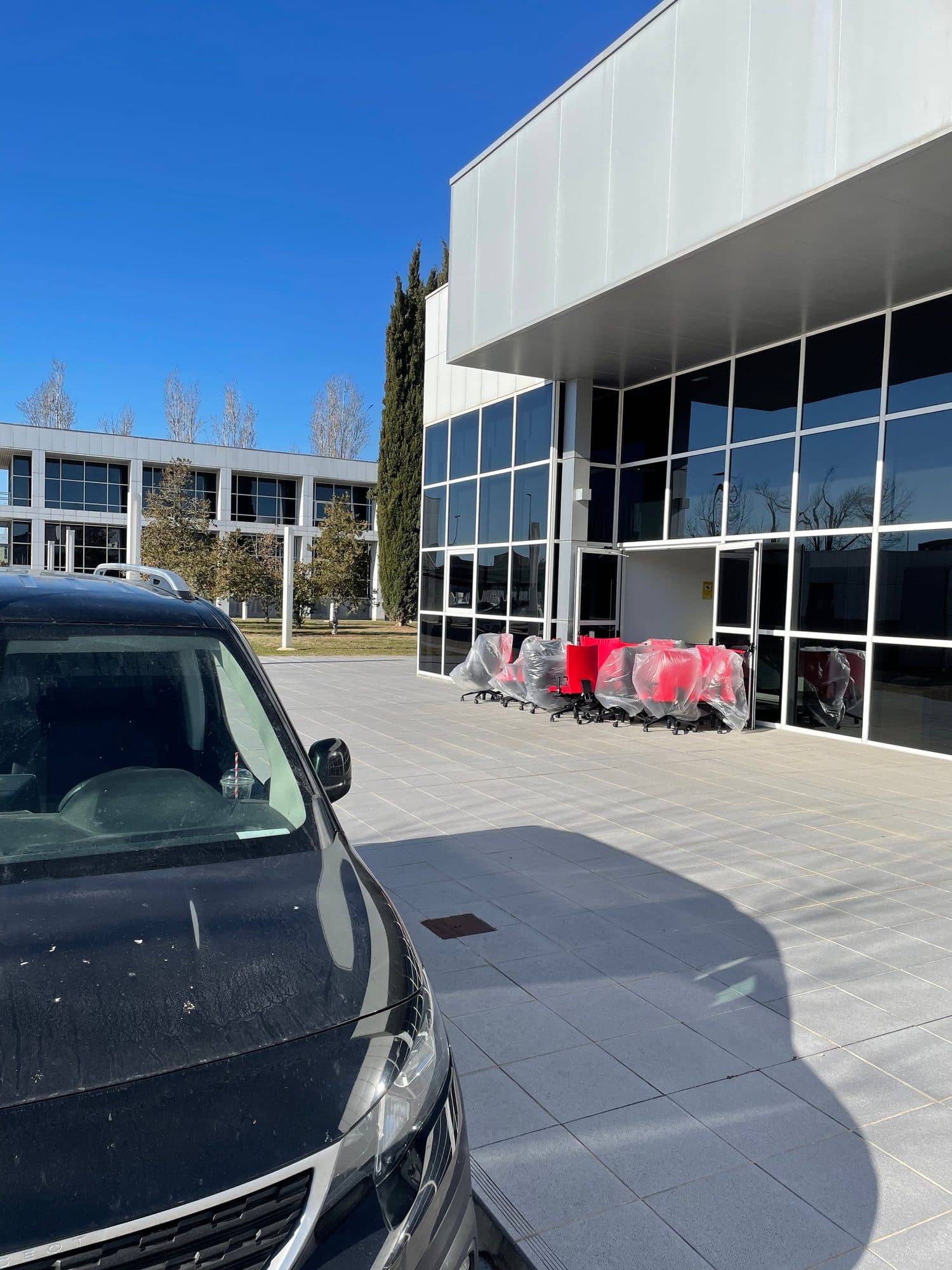 Furgoneta de reparto junto a un lote de sillas de oficina protegidas en un polígono