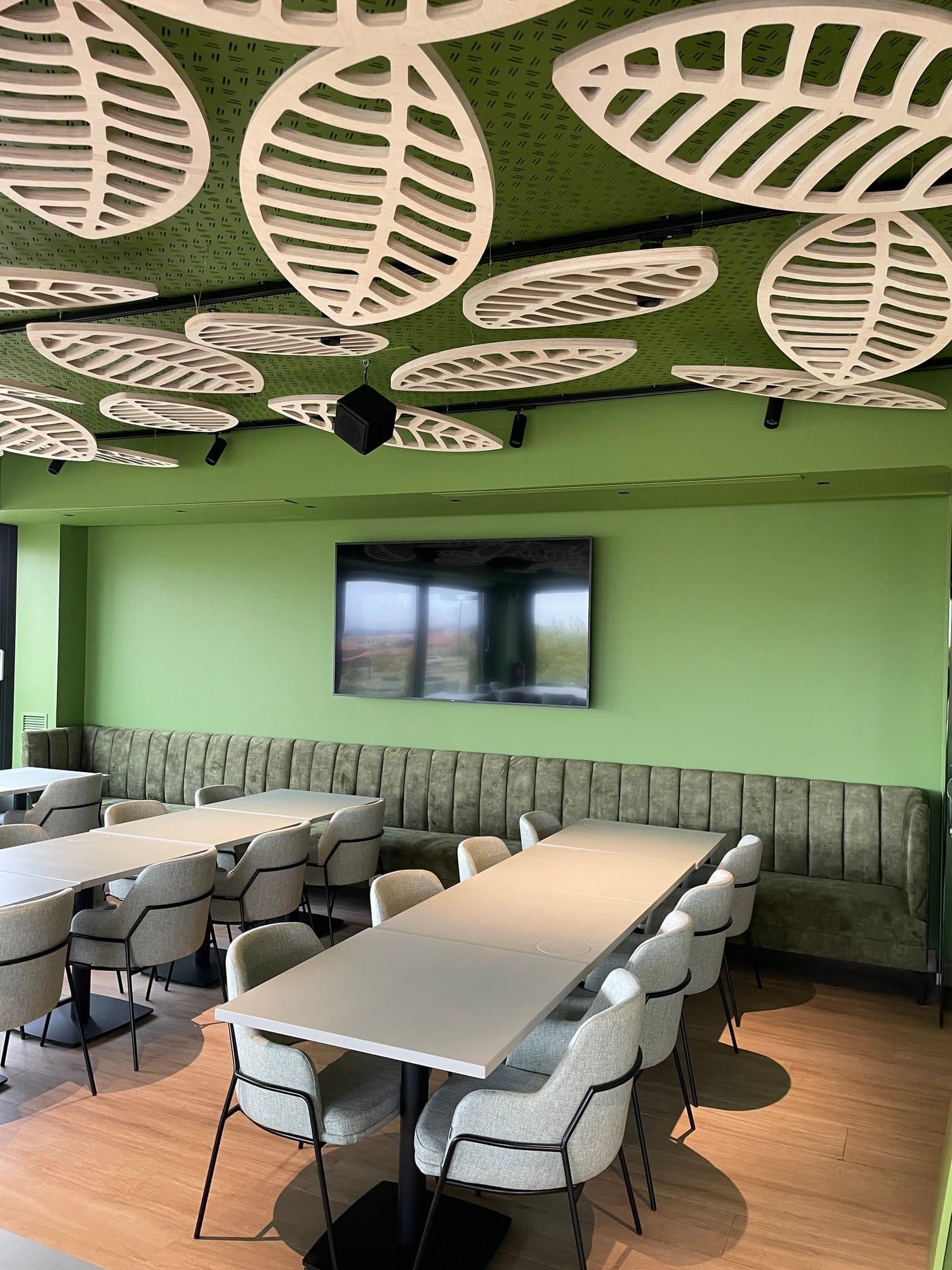 Comedor de restaurante con bancada corrida tapizada en verde a lo largo de la pared
