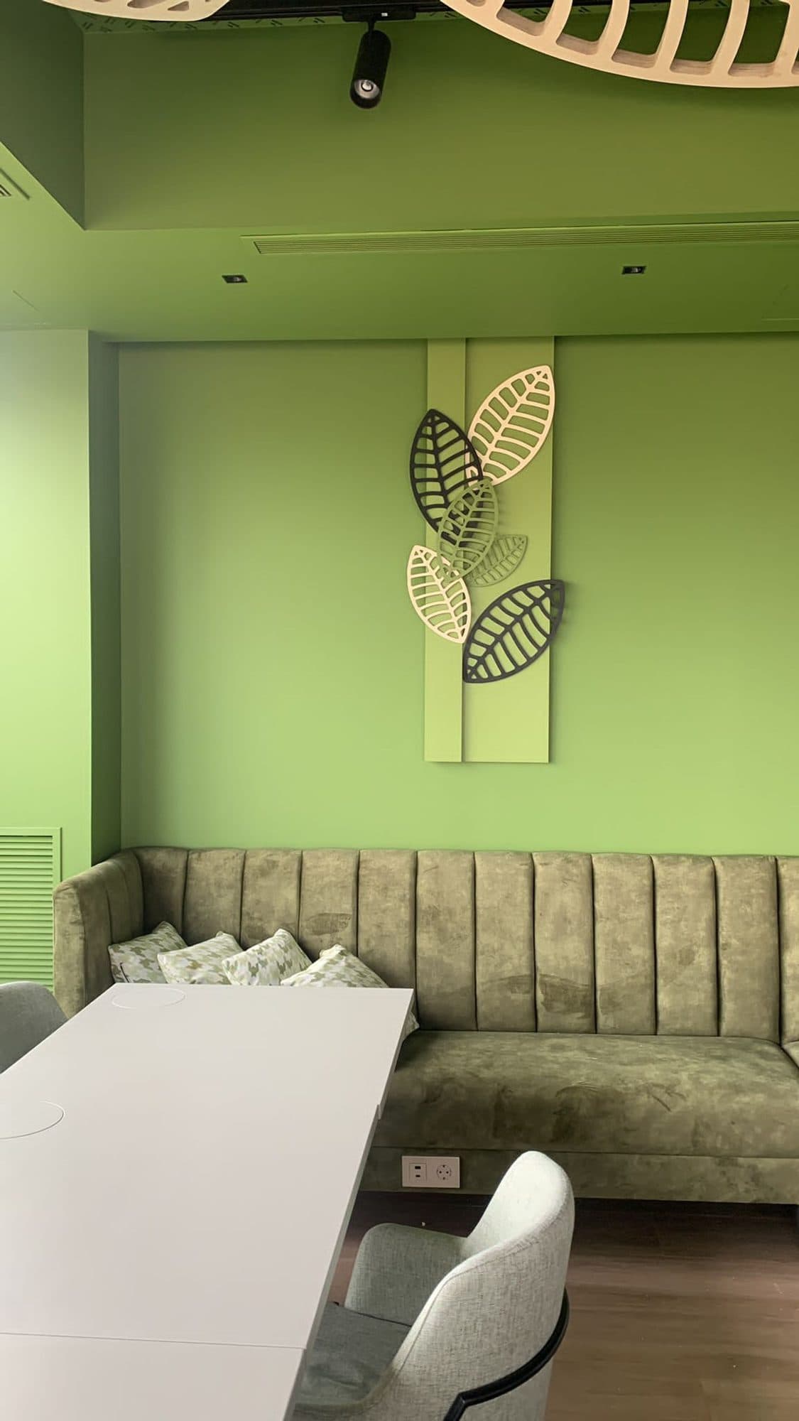 Bancada tapizada en verde con capitoné vertical en un restaurante