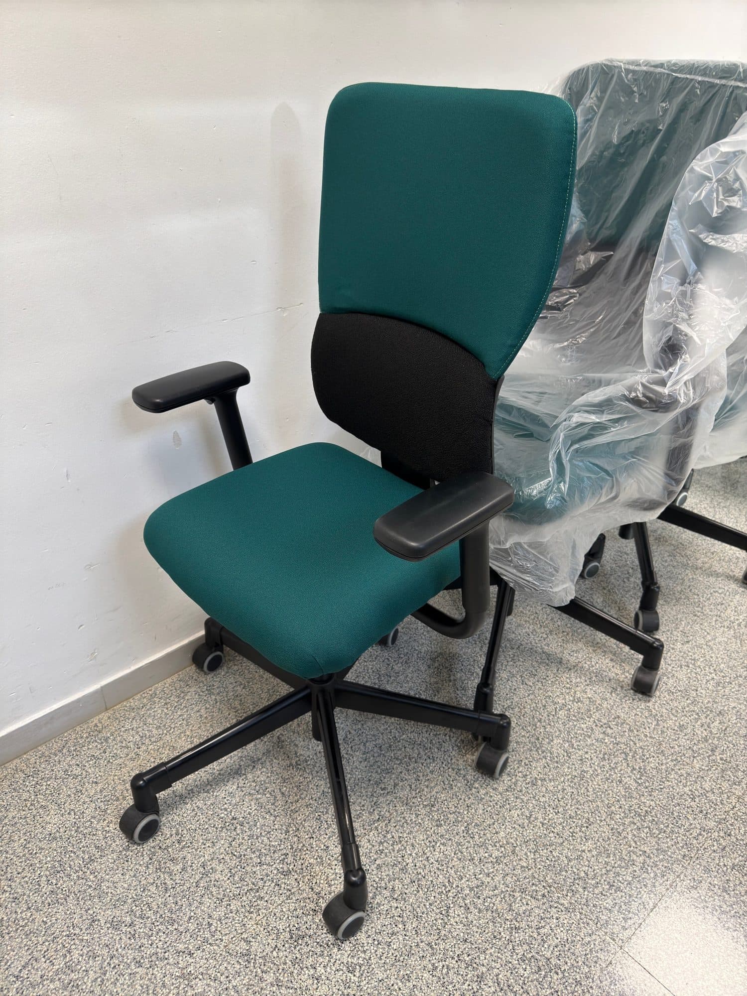 Silla de oficina retapizada en verde junto a otras protegidas para su entrega