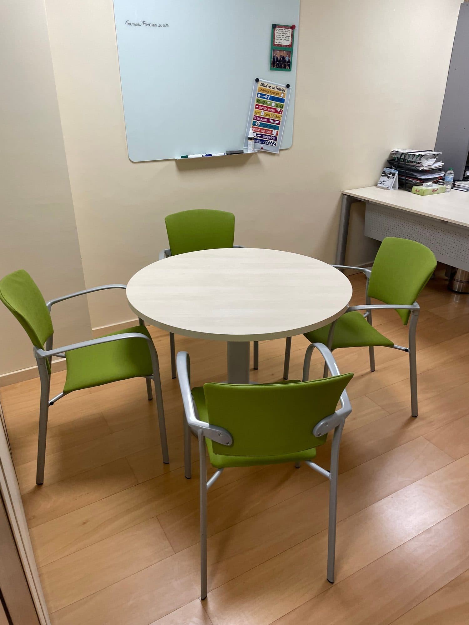 Sillas de confidente tapizadas en verde alrededor de una mesa redonda