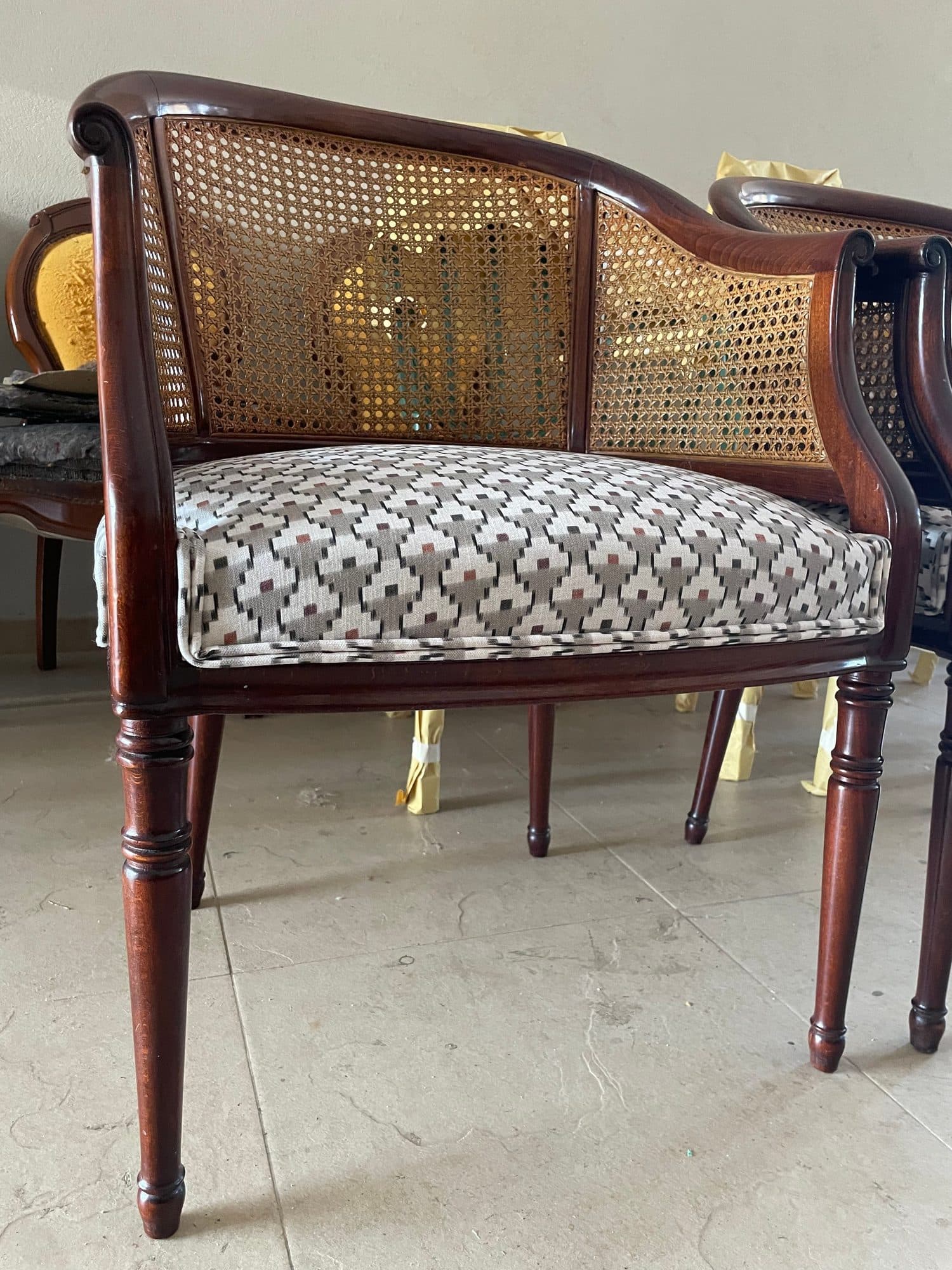 Sillón de madera con respaldo de rejilla y asiento tapizado en tejido geométrico